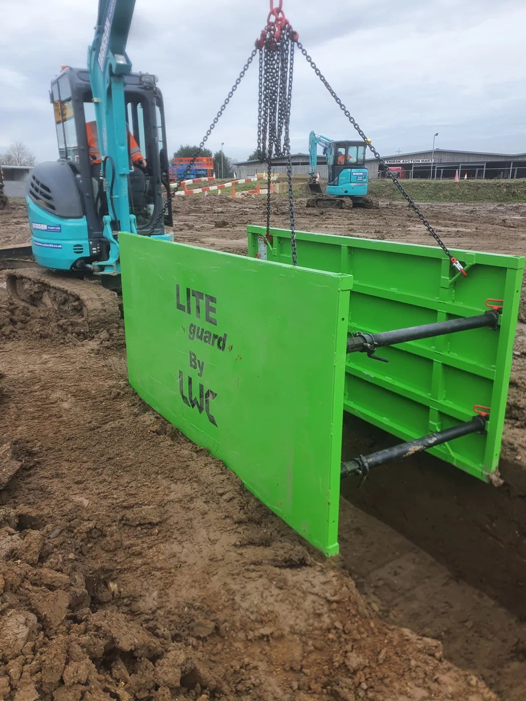 Green proprietary trench support system positioned at an excavation
